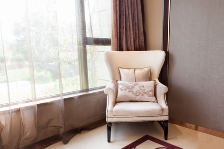 Armchair close to  the window at  a new interiors, through the window  a small garden can be seen の写真素材