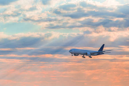 Landing airplane flying on the sky with sunshine and clouds background in the morning. Travel...