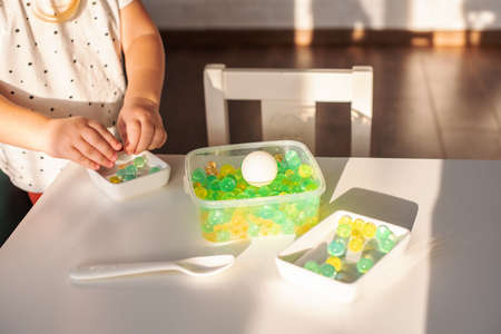 Little girl playing with sensory water beads, hydrogel balls. Sensory development and experiences,...