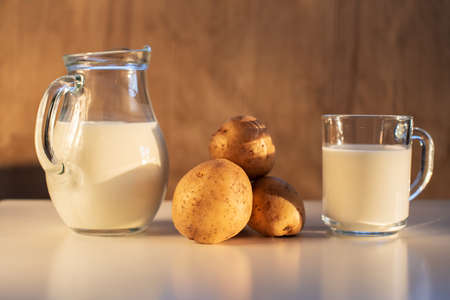 Vegan plant milk from potato in glass jar and potato tubers on the table. Concept of potato milk, vegan sustainable option, plant-based dairy. Substitute drink, healthy eating, diet, nutritionの写真素材
