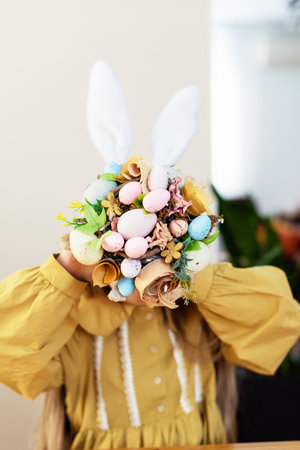 Child with easter bunny ears holding colorful egg bouquet.