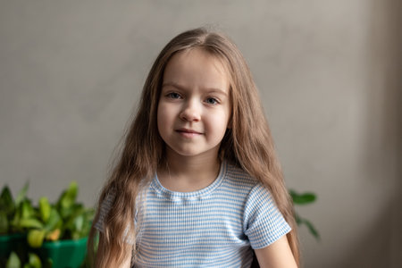 Caucasian young girl smiling indoors with long brown hair and striped shirt.の写真素材