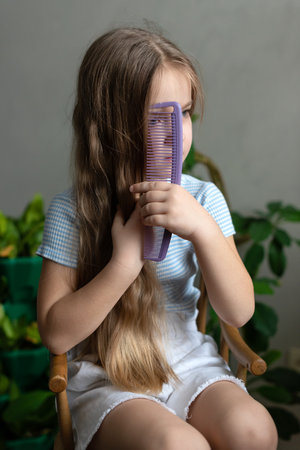 Caucasian young girl combing long hair at home.
