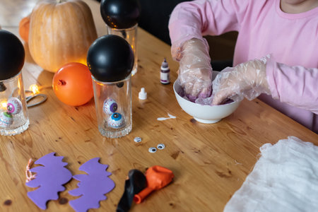 Child making halloween slime with pumpkins and decor on wooden table., Cheesecloth Ghosts, Halloween craft.の写真素材