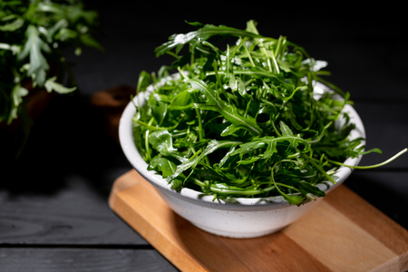 Fresh rocket salad in bowl on the wodden backgroundの写真素材