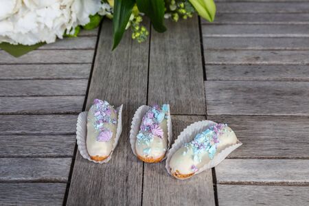 Tasty eclairs on wooden table, close up