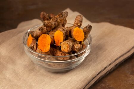 turmeric powder in jar dish on brown backgroundの写真素材