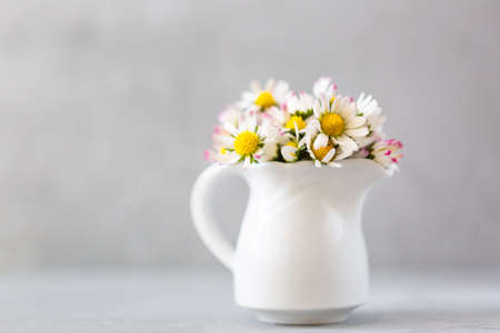 Beautiful daisy flowers in ceramic white vase on ultimate gray backgroundの写真素材