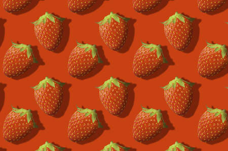 Whole strawberries fruit pattern on red color backgroundの写真素材