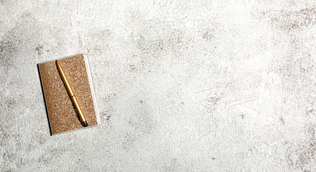 Notebook and pen on a gray concrete background. Female workspace. Top view, flat lay, copy spaceの写真素材