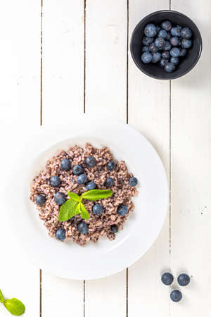 Delicious risotto with blueberries served on white wooden table, flat layの写真素材