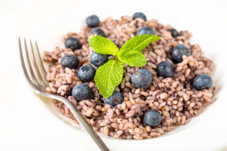 Delicious risotto with blueberries served on white wooden tableの写真素材