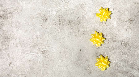 Yellow gift bow on concrete background template for posters and banners