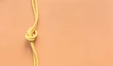 Yellow string knotted on a orange colour backgroundの写真素材