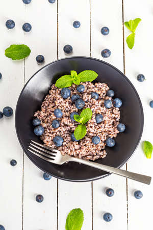 Delicious risotto with blueberries served on white wooden table, flat layの写真素材