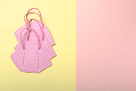 FFP2 face mask to protect from infectious covid-19 on pastel yellow and pink surface.の写真素材