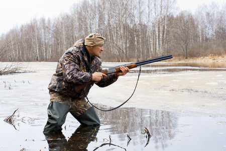 a hunter with a gun on the lakeの写真素材