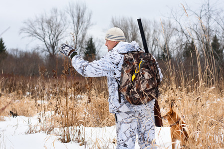hunter with gun and dog on snowy fieldの写真素材