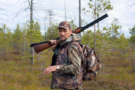 hunter walking with gun on the swamp