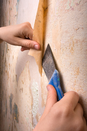 hands removing wallpaper from wallの写真素材