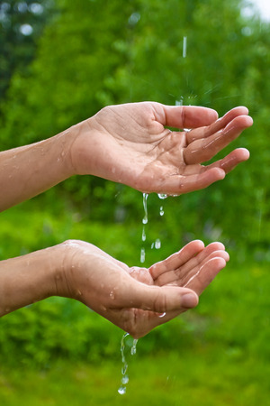 hands catching raindrops on blurred backgroundの写真素材