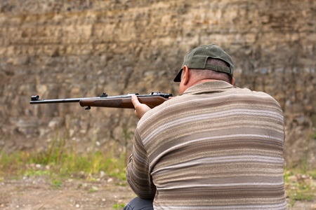 back view of hunter aiming from a rifle