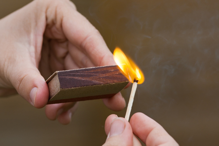 hands striking a match on blurred background, closeupの写真素材
