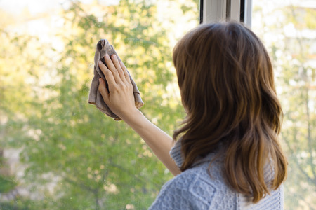 young woman washing window in the room