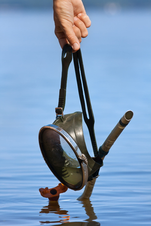 hands holding old diving mask on water backgroundの写真素材