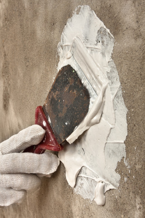 hand plastering concrete wall with putty knife during repair
の写真素材