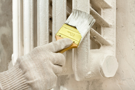 hand in glove painting radiator central heating with brushの写真素材
