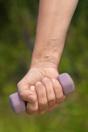hand with dumbbell on green blurred backgroundの写真素材