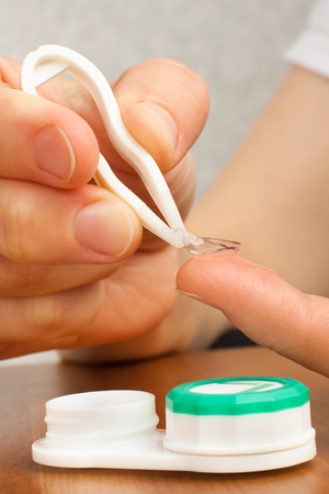 hands of woman putting on contact lensesの写真素材