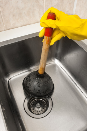 hand using a plunger to cleaning a clogged sinkの写真素材
