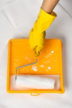 hand with roller and tray with white paintの写真素材