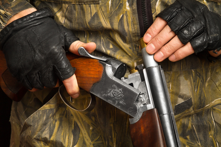 the hands of the shooter in gloves put a cartridge in the shotgunのeditorial素材
