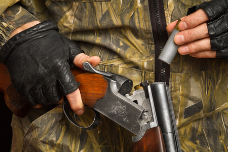 hands of the shooter in gloves put a cartridge in the shotgunのeditorial素材