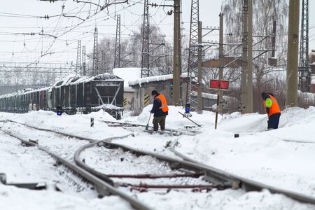 Perm, Russia - 17 February, 2019. Workers clear the rails of snow at the Cable stationのeditorial素材