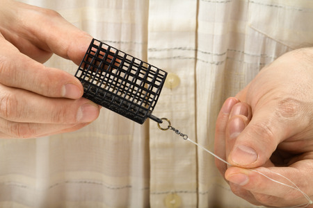 the cage feeder is in hands of  angler, closeup