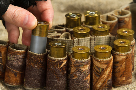 the hand of the hunter fills his bandolier with ammo, closeup