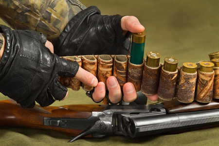 hunter fill his bandoleer with ammunition for the shotgun, closeupの写真素材