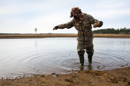 duck hunter putting a duck decoy on the shallow waterの写真素材