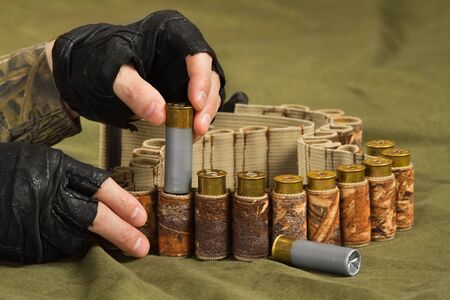 hands of hunter in gloves fill his bandoleer with ammunition on the tarp, closeupの写真素材