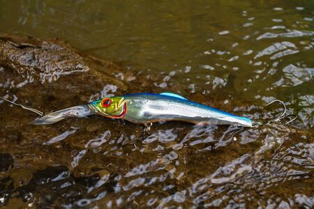 blue shiny wobbler caught on an old overgrown snag in the water while fishingの写真素材