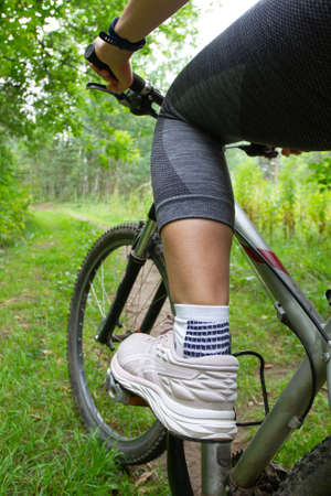 the female cyclist stopped her bike on a forest path, close upの写真素材