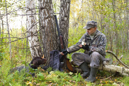 hunter sits on a fallen tree and feeds the gundog with his handsの写真素材