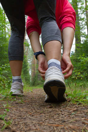 A jogger tightens the laces on his sneakers before running in the parkの写真素材