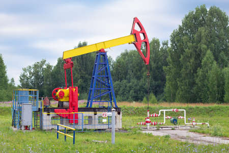 a single oil pumpjack stands in a clearing among the treesの写真素材