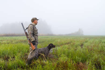 the hunter and his dog went out on a damp meadow on a foggy morning to huntの写真素材