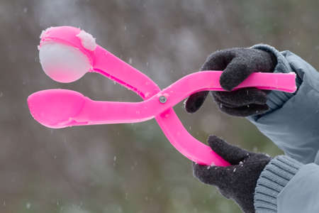 hands of a woman dressed in gloves hold the form for making a snowballの写真素材